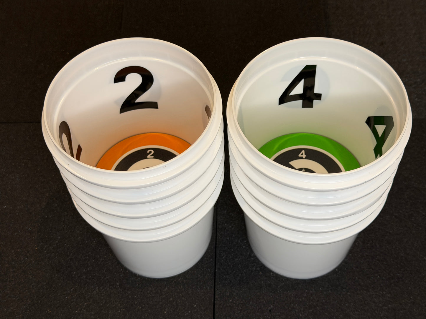 Two stacks of white cups with numbers and colored rings on a black background