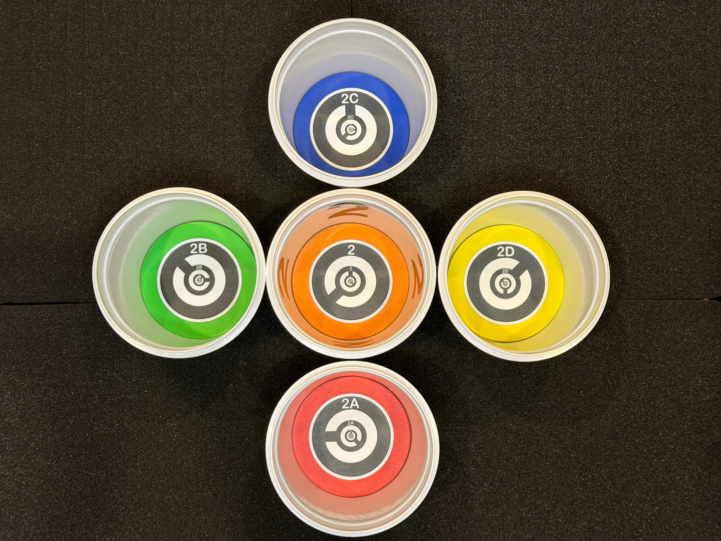 Five colorful plastic cups with circular designs on a black background