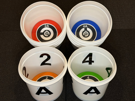 Four white cups with numbered and color-coded targets on a black background